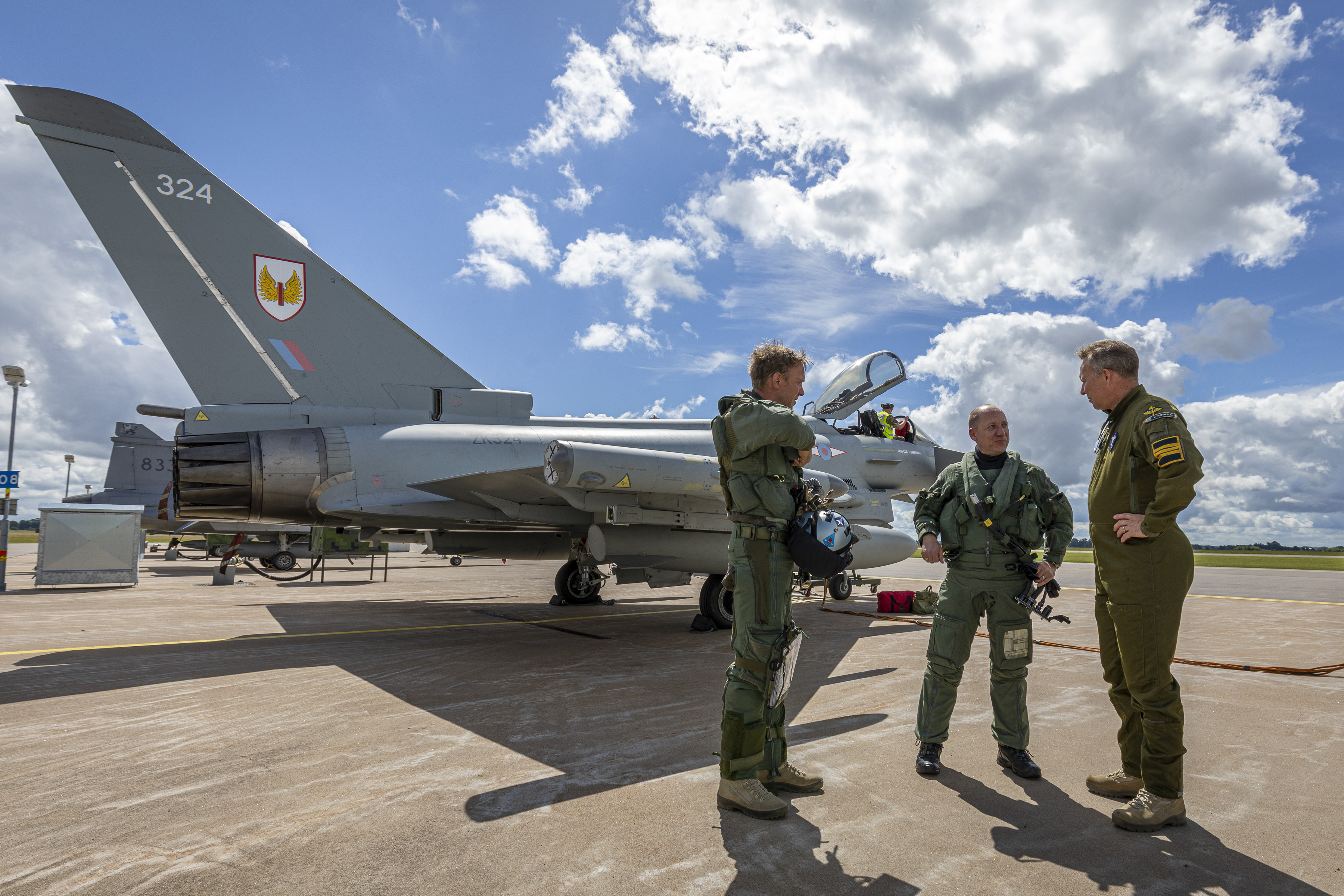 Image shows RAF aviators standing in discussion by Typhoon aircraft.